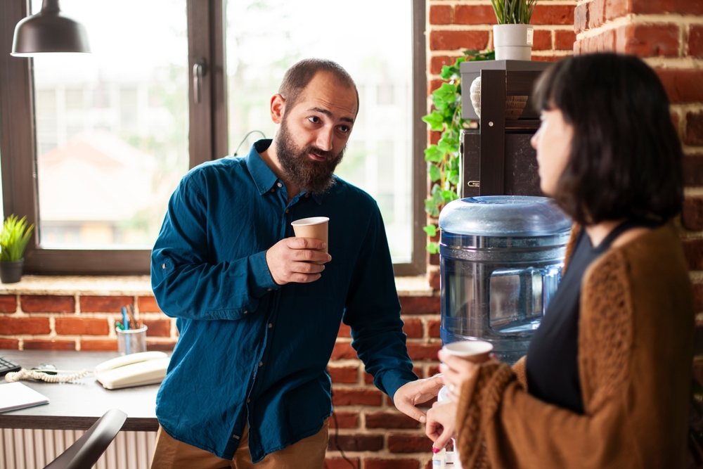 Businessman,and,woman,share,conversation,near,water,cooler,in,brick