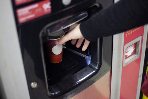 Hot,coffee,from,the,vending,machine.,a,hand,reaches,for